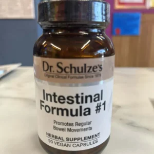 A brown bottle of Dr. Schulze’s Intestinal Formula #1 (90 Vegan Capsules) organic herbal supplement sits on a marble surface.
