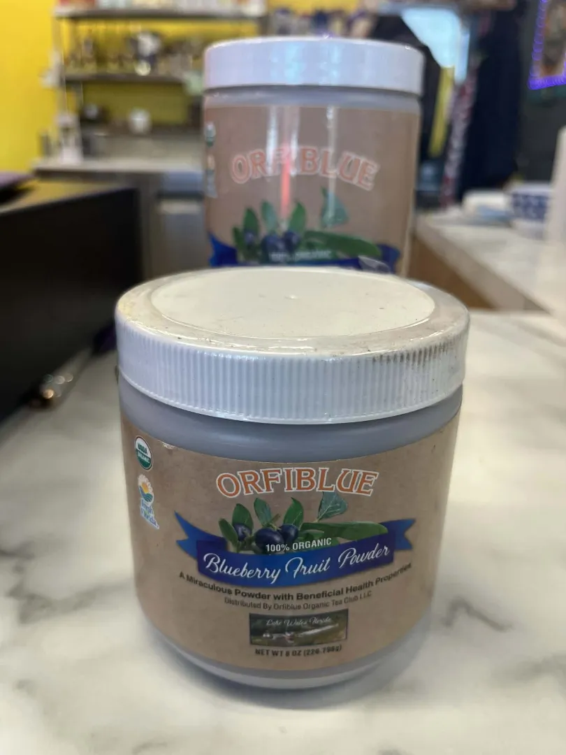 Two jars of Dr. Schulze's Tea Leaf Powder are displayed on a counter, with one jar in the foreground and one slightly blurred in the background. This vegan-friendly powder is perfect for healthy lifestyles.